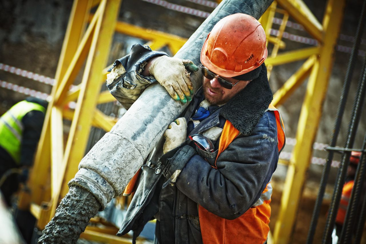 our-services-01 Construction worker in safety gear handling equipment on an active site.